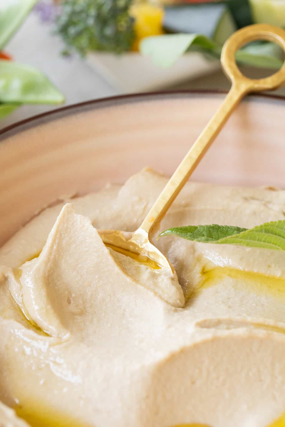 Homemade hummus appetizer with gold spoon.