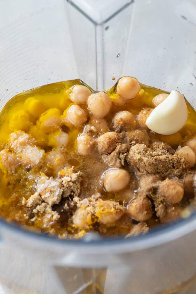 Chickpeas, garlic, tahini, cumin, ginger, lemon juice and olive oil in a blender to make hummus.