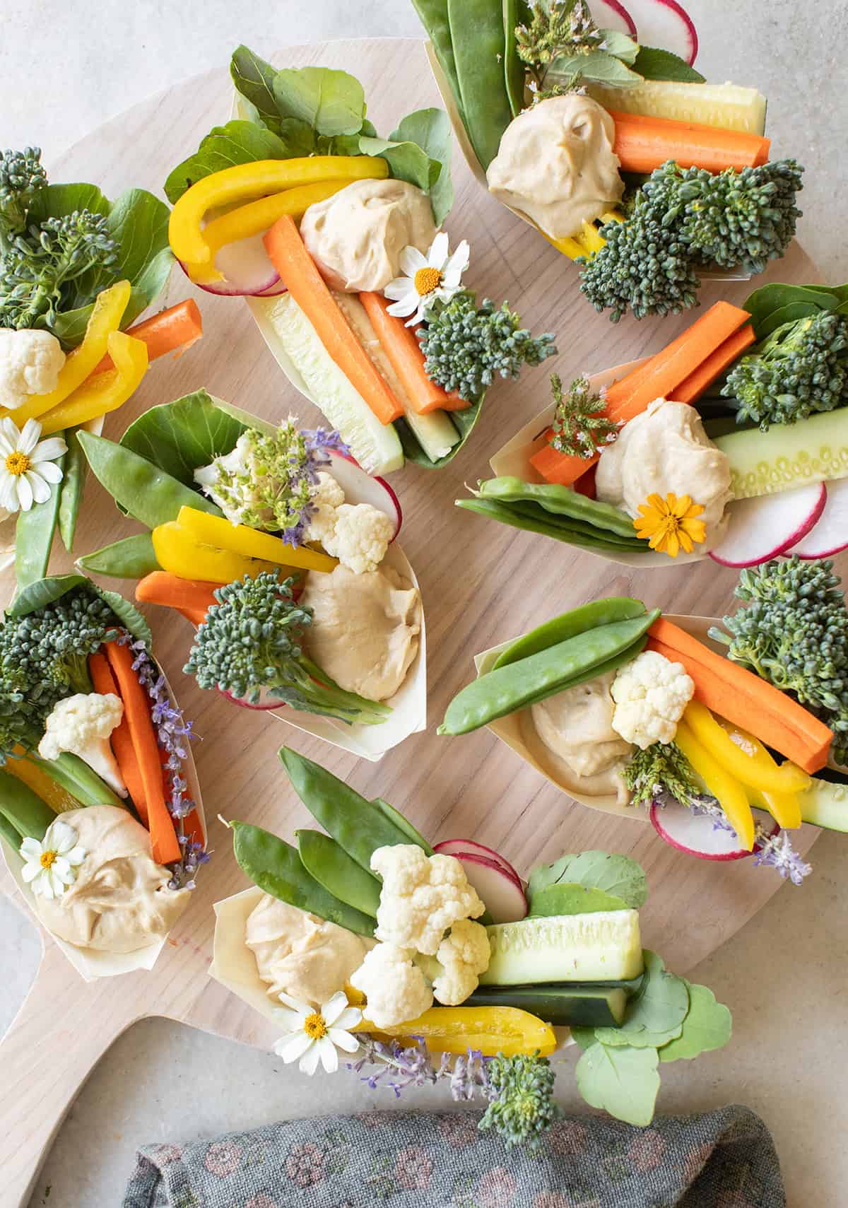 Hummus appetizer on small plates with freshly sliced vegetables. 