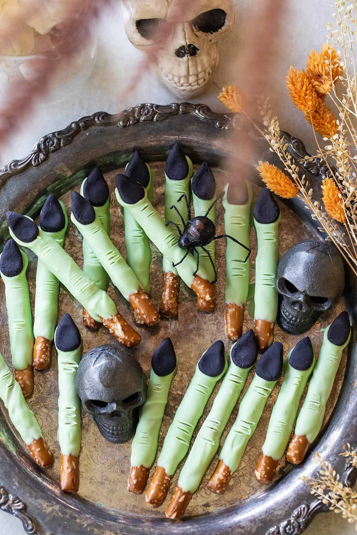 Green witch finger pretzels on a platter for Halloween.