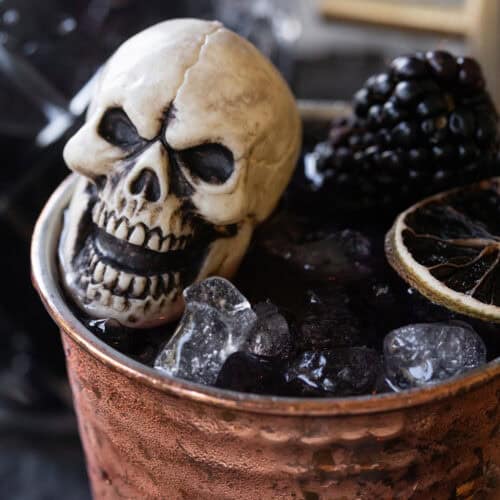 Halloween Moscow mule with blackberries, ginger and black vodka served in a copper cup.