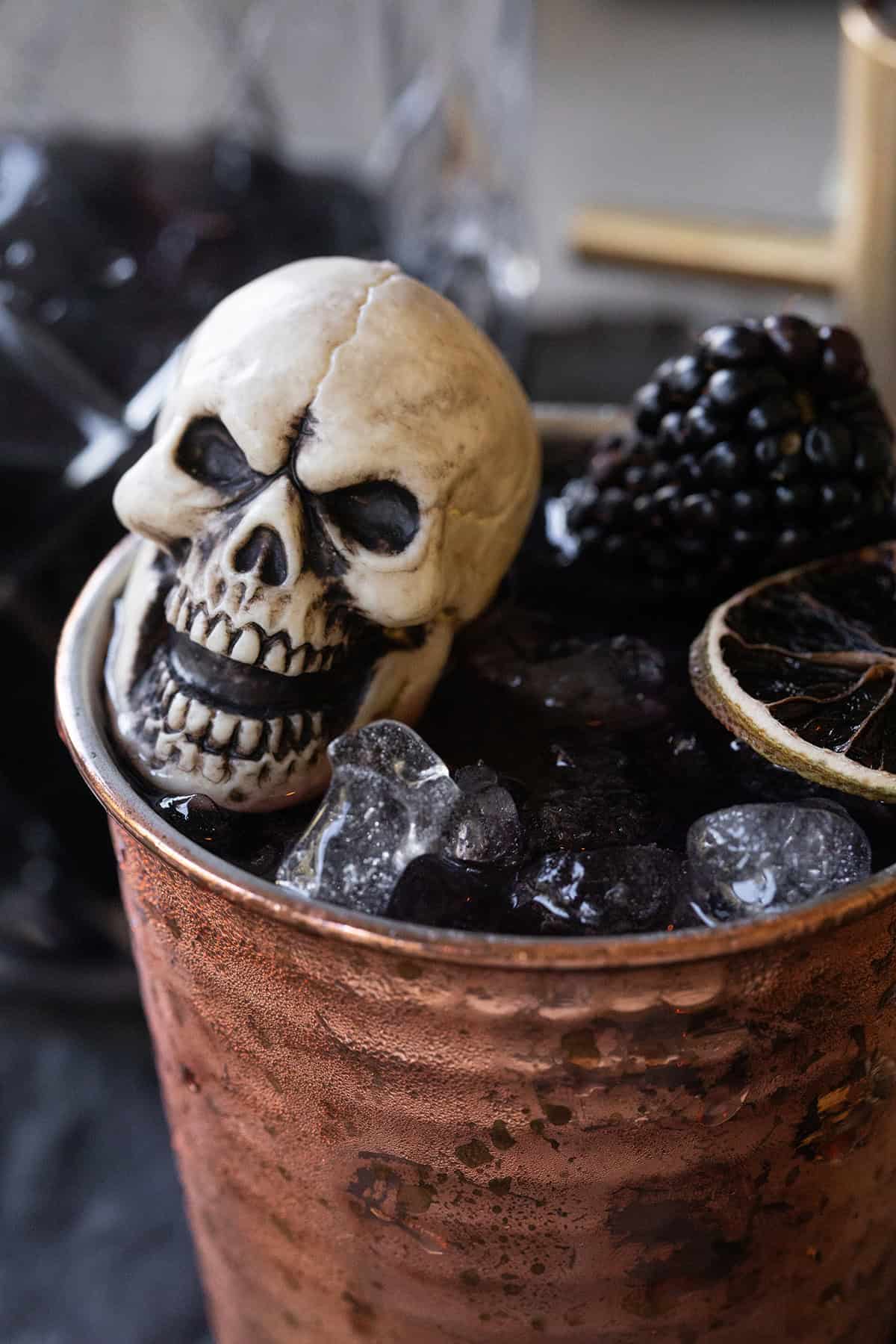 Halloween Moscow mule with blackberries, ginger and black vodka served in a copper cup.