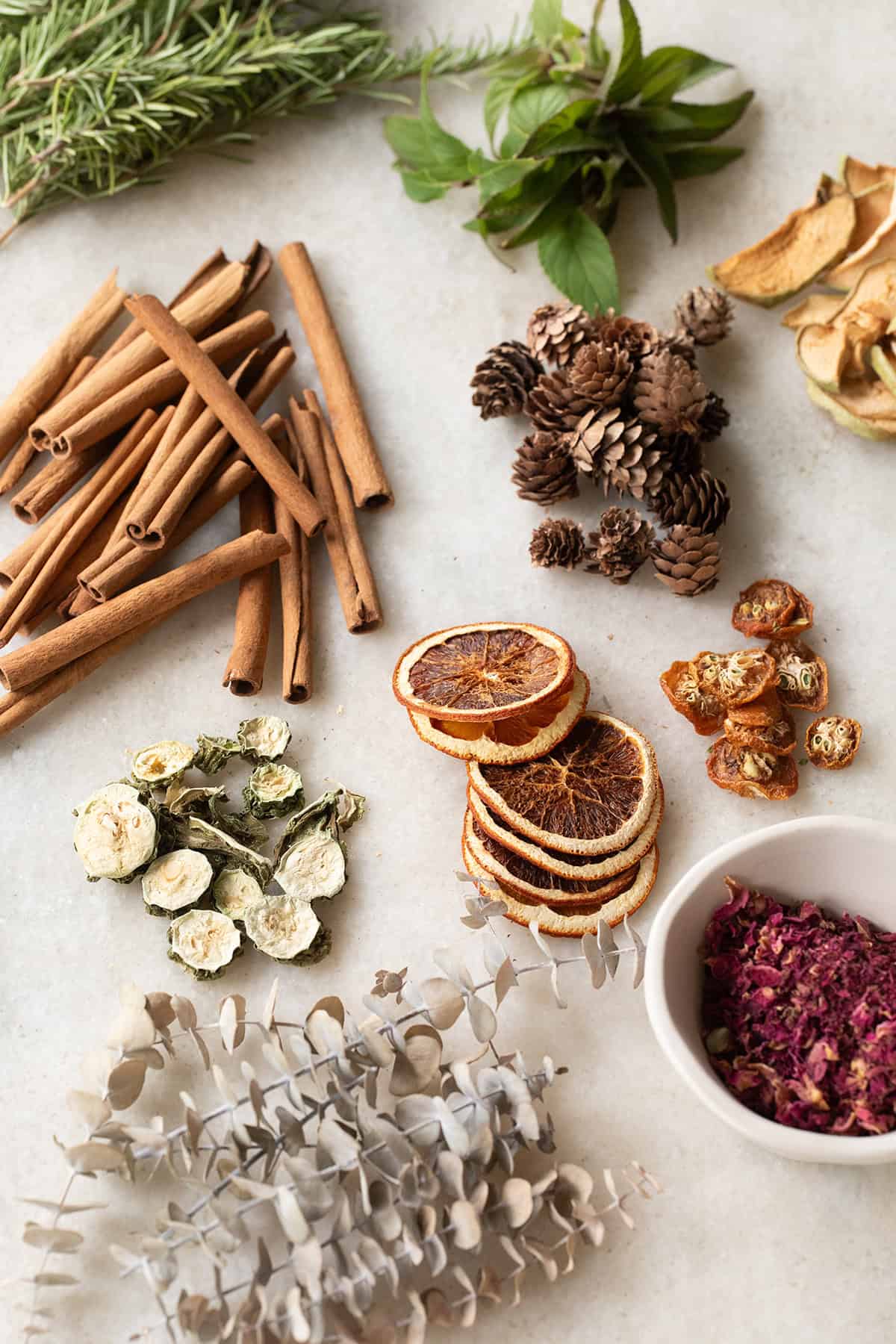Dried cinnamon, rosemary, orange slices and herbs on a table.