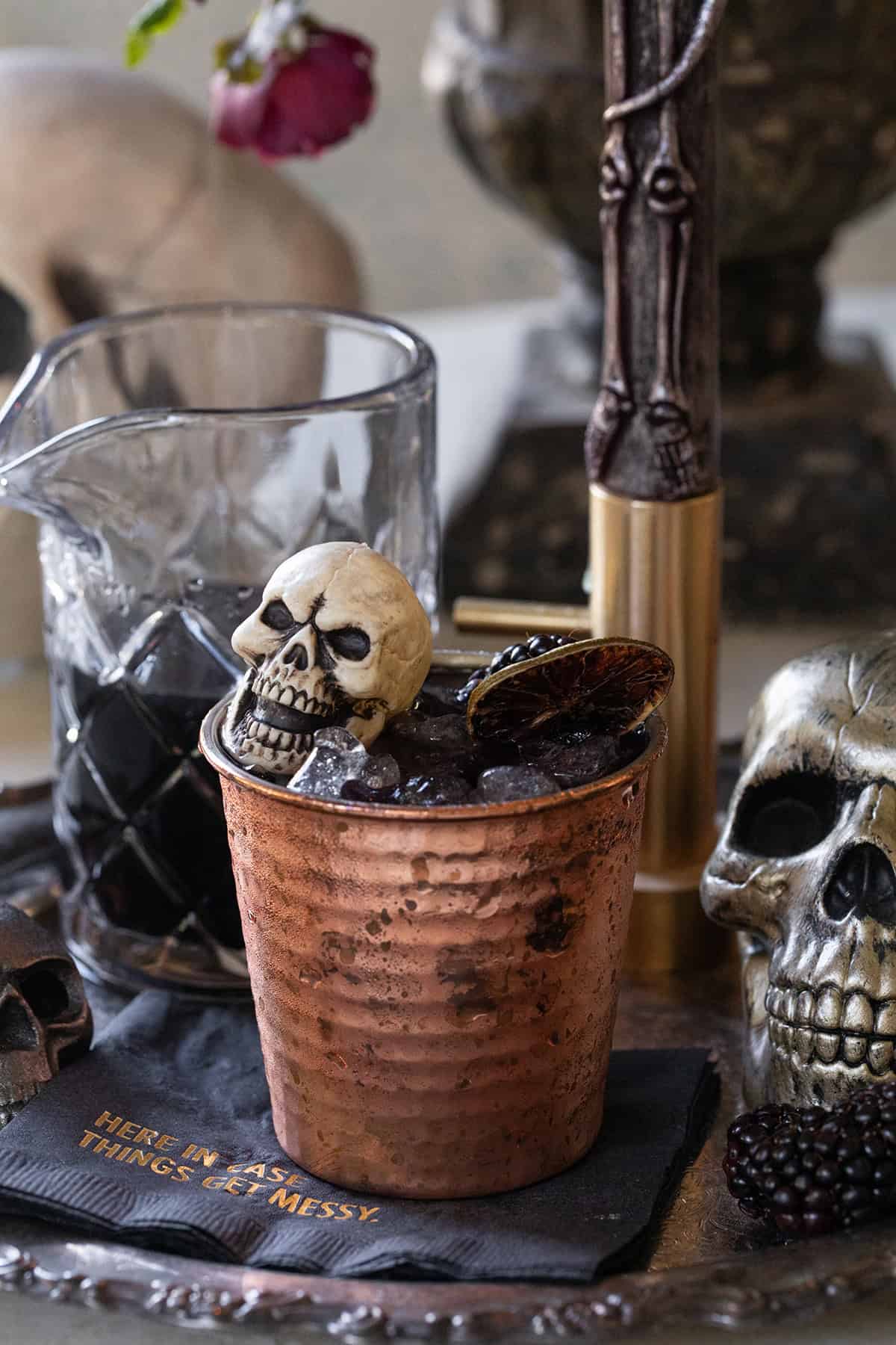 Halloween cocktail recipe served in a copper mug with skeleton decor.