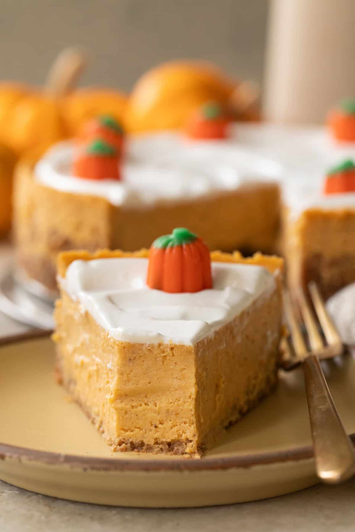 Slice of pumpkin cheesecake with creamy topping.