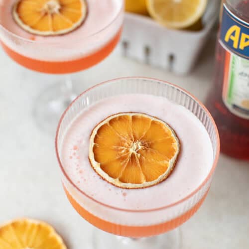 Aperol Spritz recipe with an orange slice and a creamy foam topping.