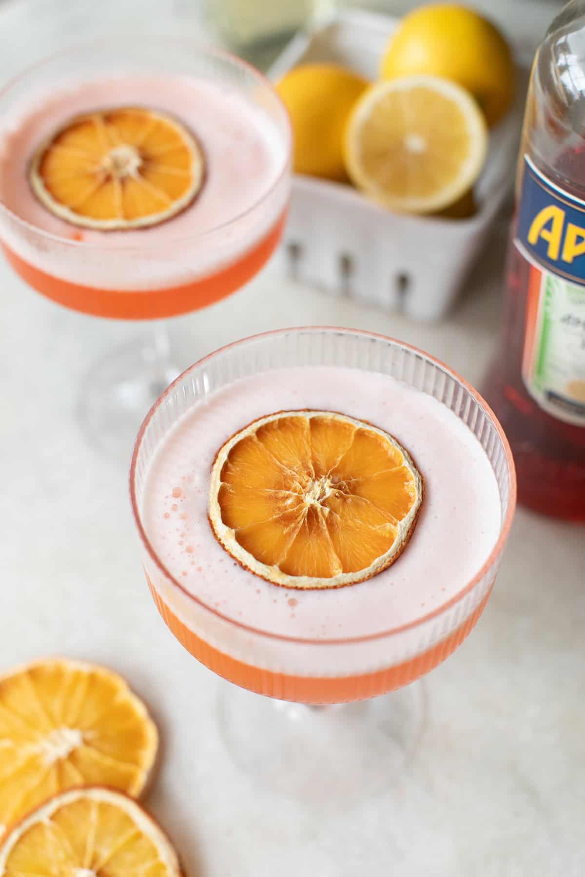 Aperol sour recipe with an orange slice and a creamy foam topping. 