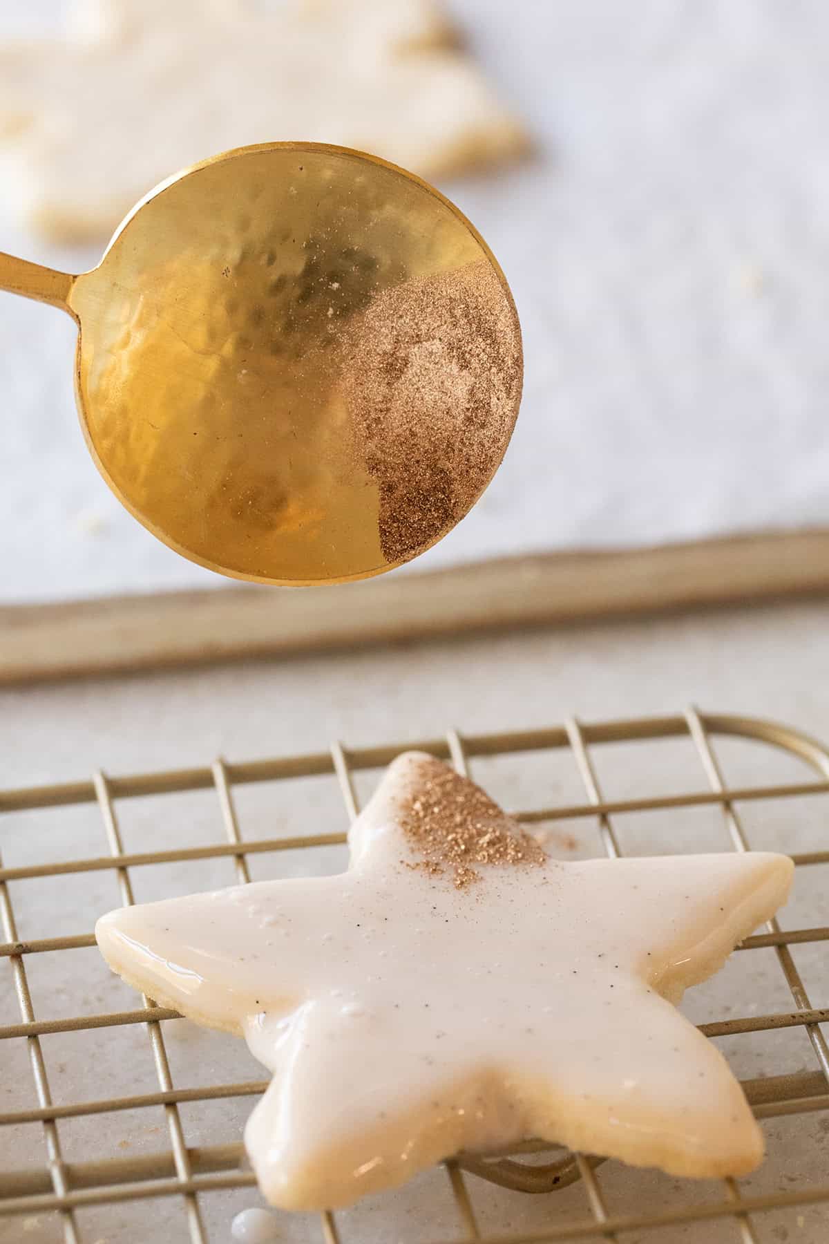 Adding edible gold glitter to a glazed shortbread cookie cutout.