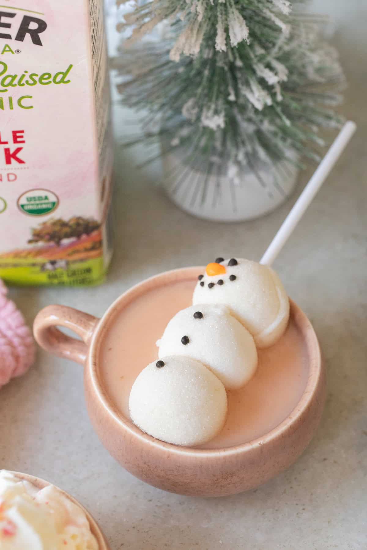 Pink hot chocolate with a snowman marshmallow on the top.