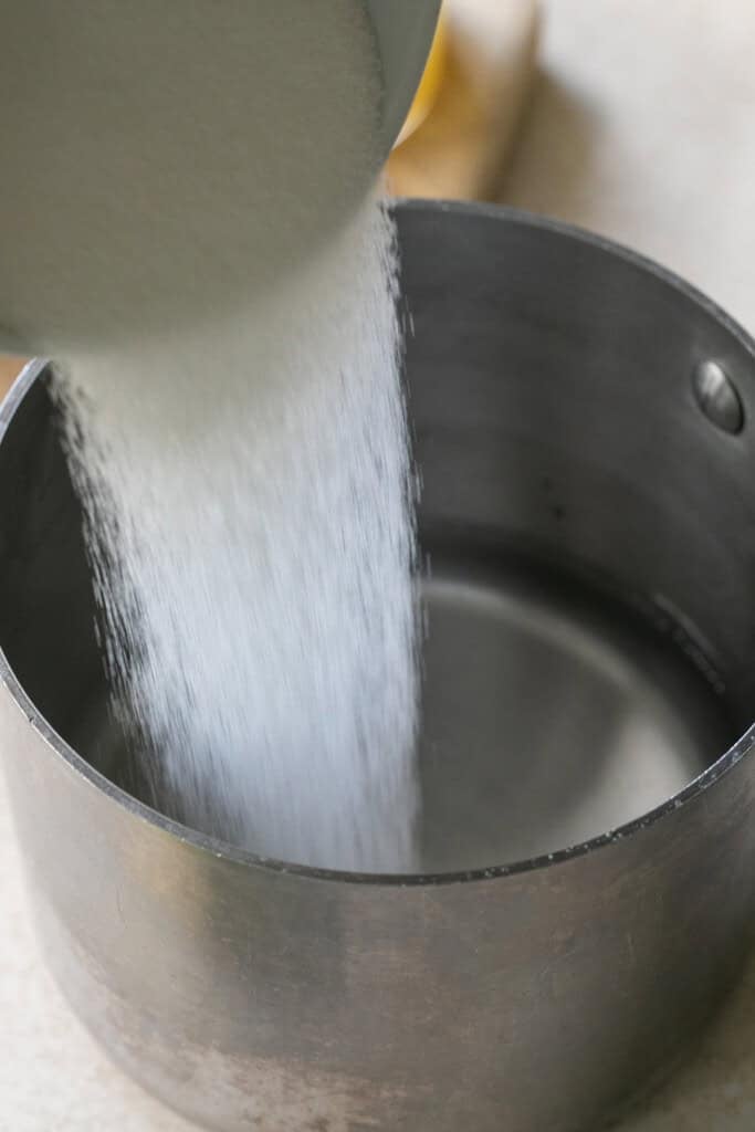 Pouring sugar into a saucepan.