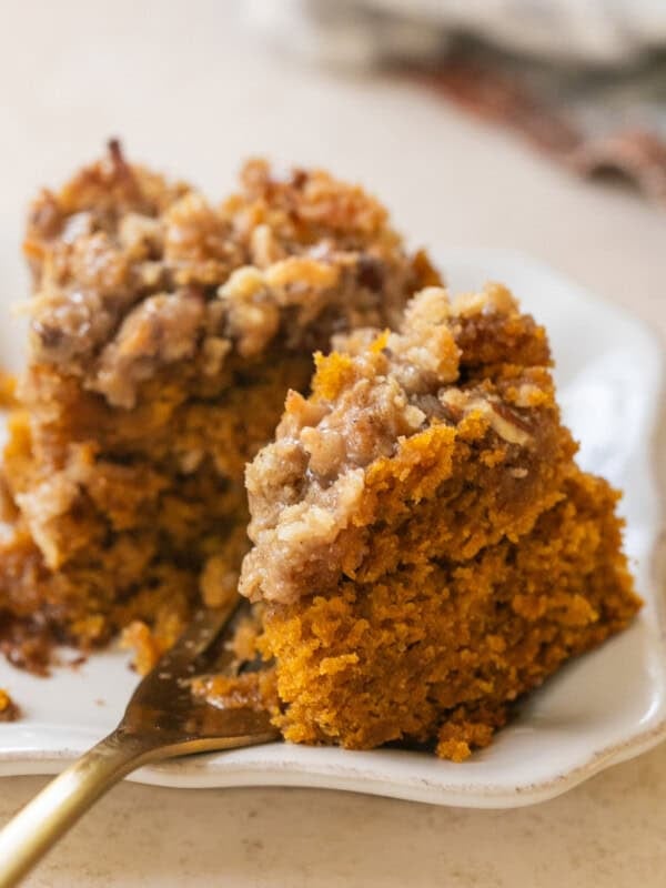 Slice of pumpkin coffee cake with coconut pecan crumb topping and cinnamon spice glaze.