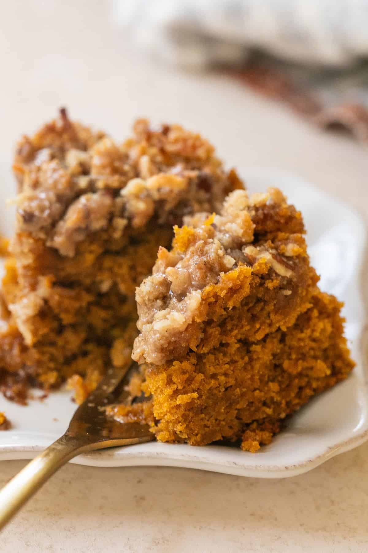 Slice of pumpkin coffee cake with coconut pecan crumb topping and cinnamon spice glaze.