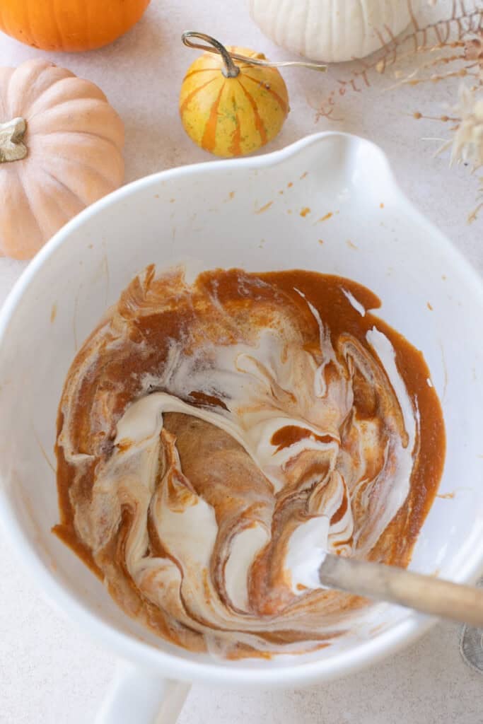 Mixing a pumpkin mousse filling in a bowl.