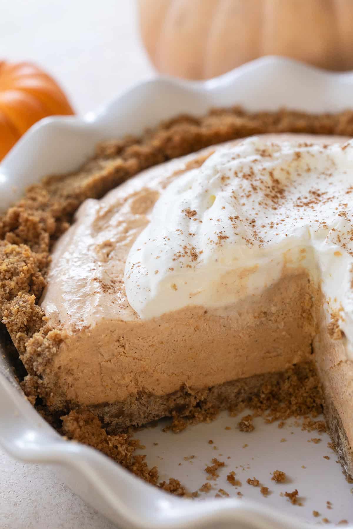 A slice taken out of a pumpkin mousse pie with a Graham cracker crust.