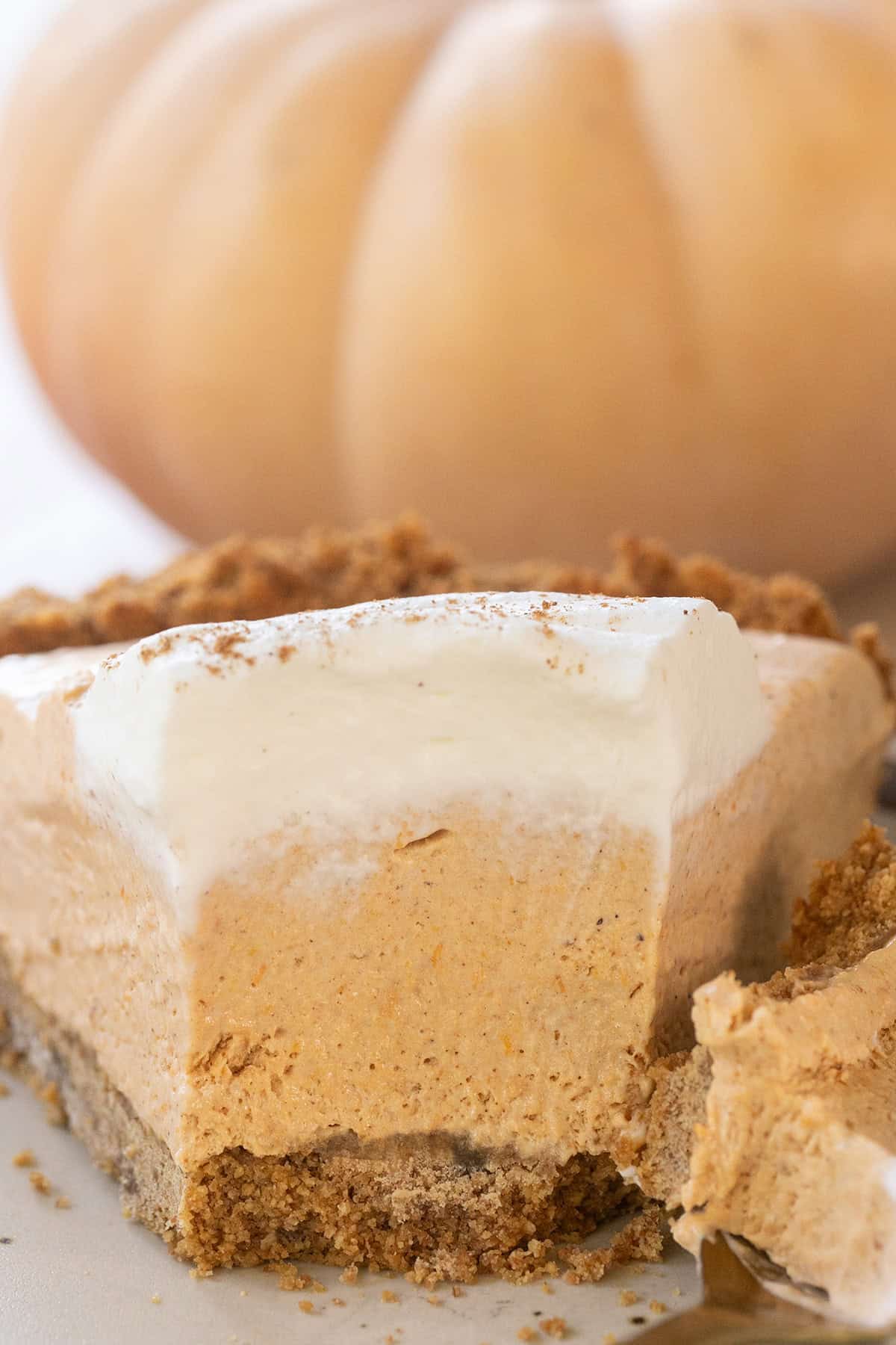 A creamy Frozen Pumpkin Mousse Pie with a slice removed, showing its fluffy mousse filling and buttery graham cracker crust.