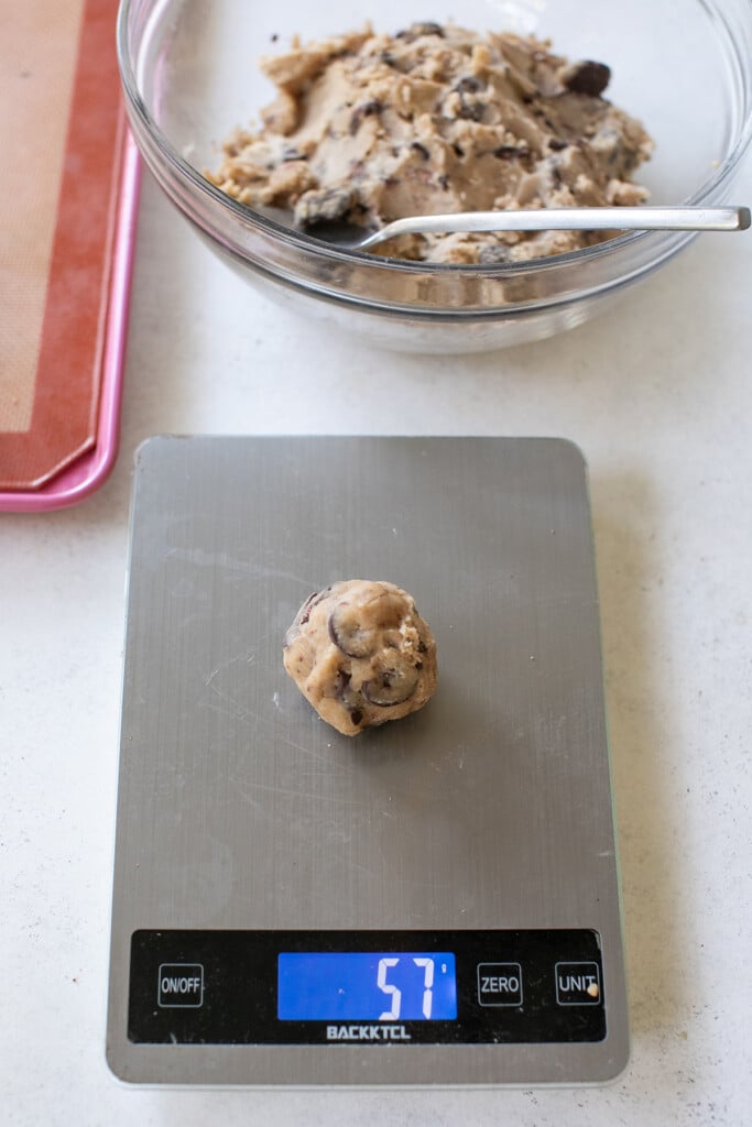 Weighing each brown butter cookie ball on a kitchen scale.