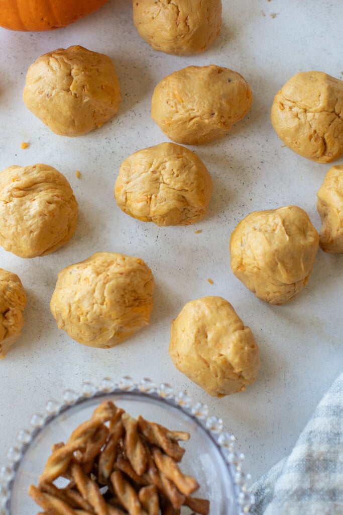 Rolling pumpkin dough into balls to make rolls. 