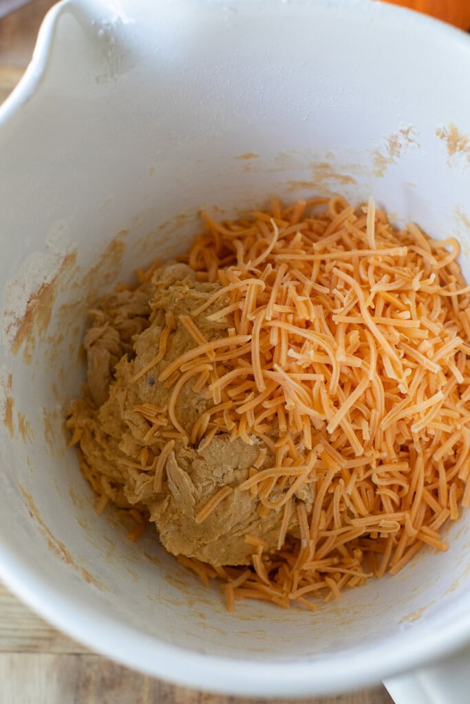 Yeast mixture and pumpkin puree being mixed in a large bowl for pumpkin roll dough.