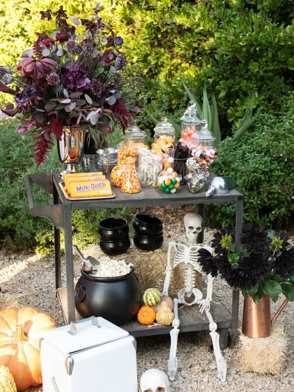 Halloween movie candy cart filled with jars of candy, popcorn and flowers.