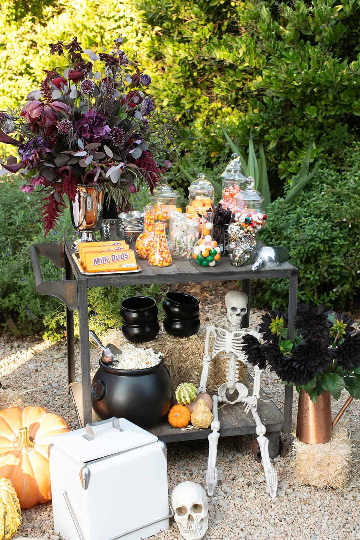 Halloween movie candy cart filled with jars of candy, popcorn and flowers.