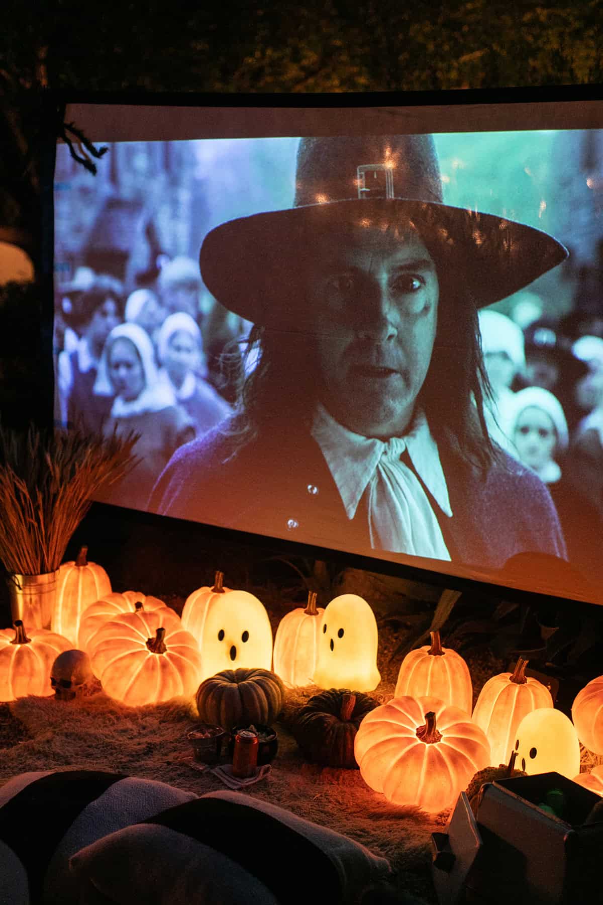 Outdoor movie with glowing pumpkins and a giant movie screen.