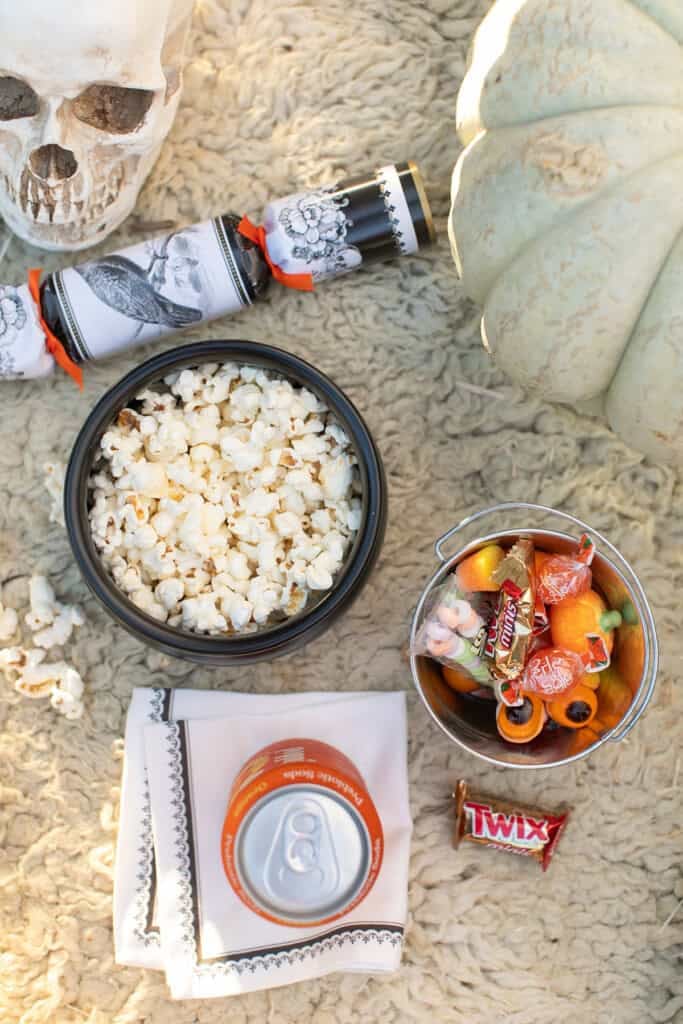 Outdoor Halloween movie snacks with candy and popcorn.