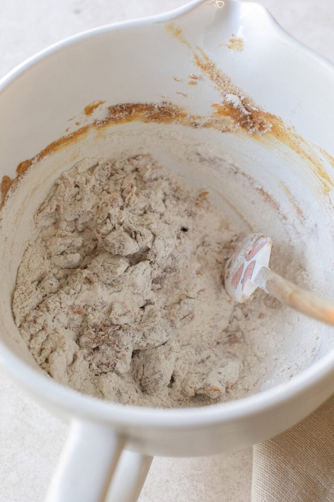Pouring dry ingredients into wet ingredients for pumpkin snickerdoodles.