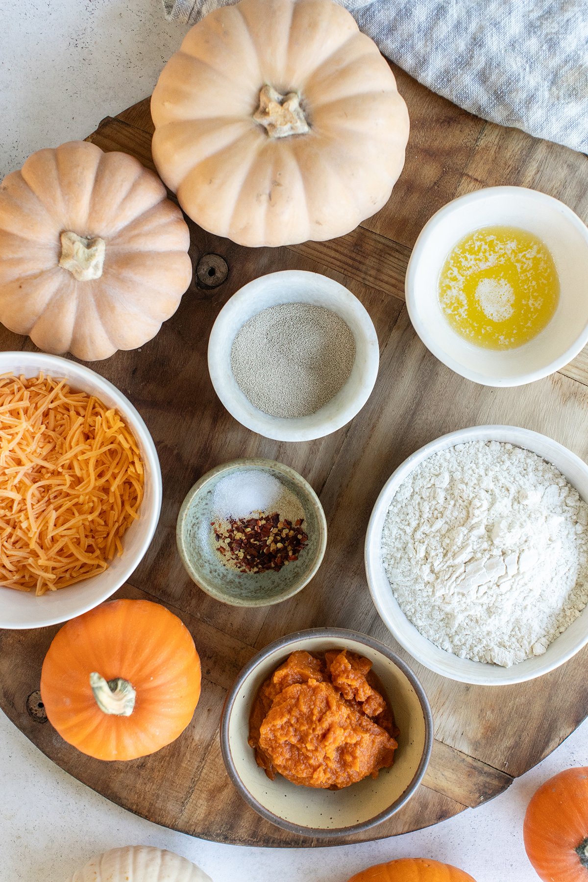 Melted butter, flour, pumpkin, water and yeast on a board to make pumpkin rolls.