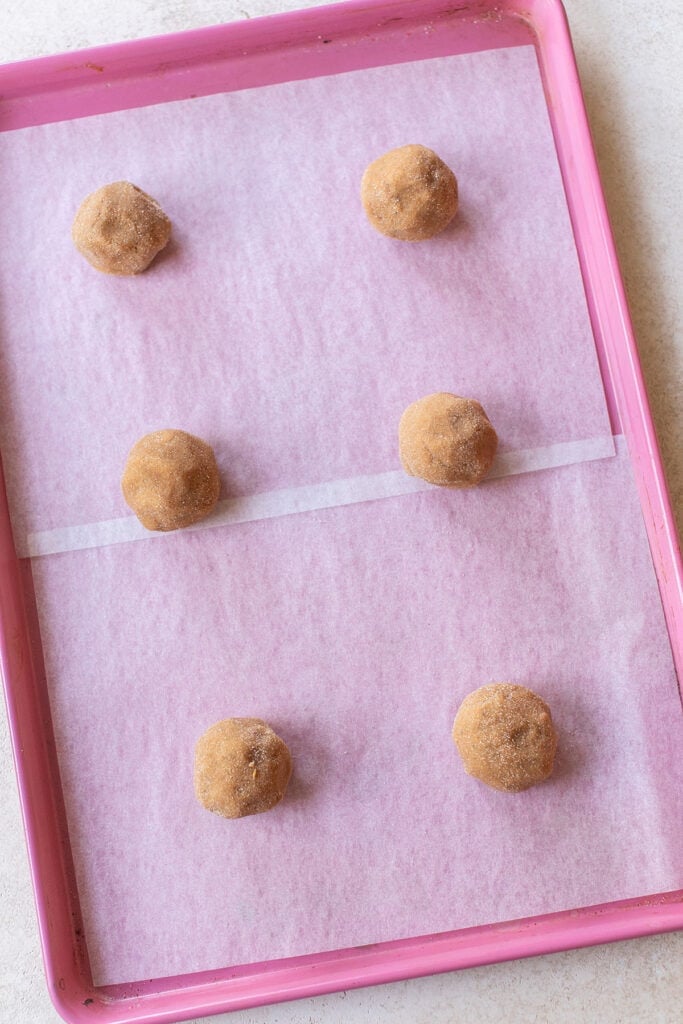 Pumpkin snickerdoodle dough balls on parchment-lined baking sheet