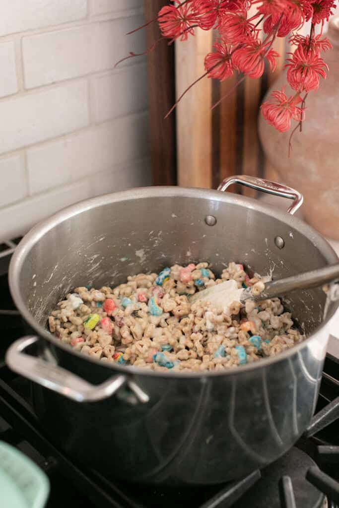 Mixing Lucky Charms cereal into melted marshmallow mixture