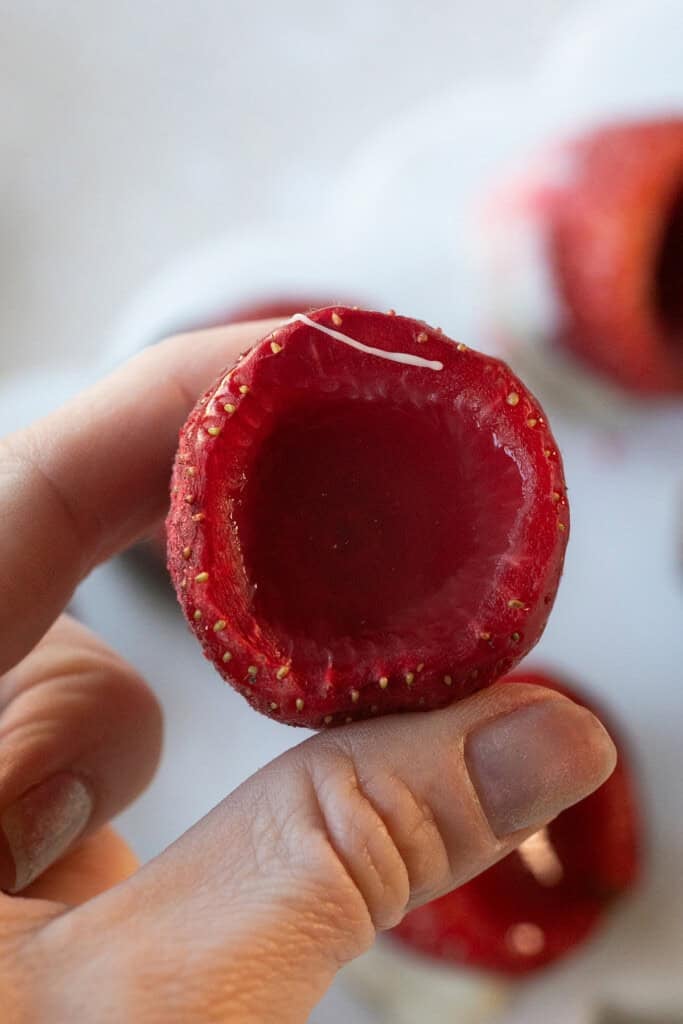 Close-up of a hollowed-out strawberry with a smooth jello shot inside.