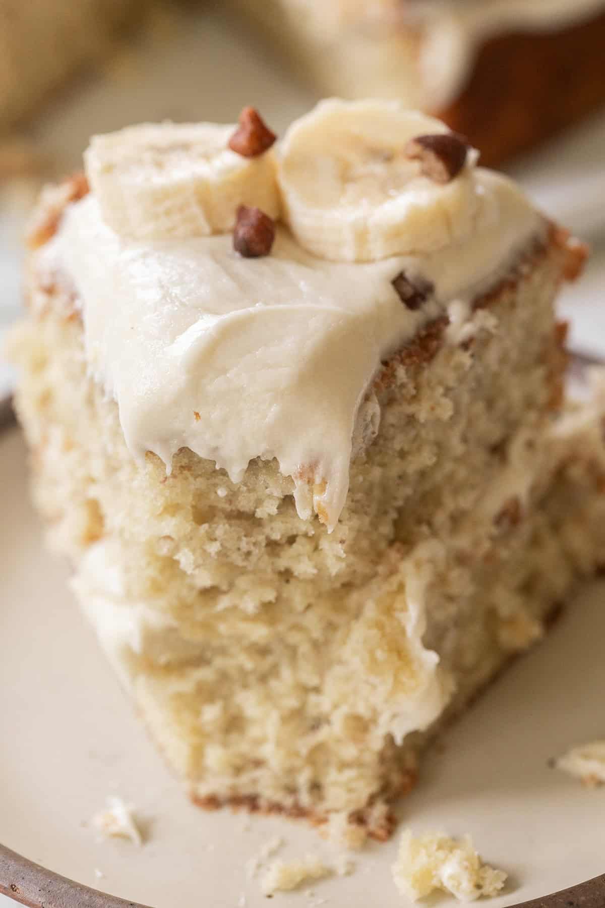 Delicious banana cake topped with cream cheese frosting and fresh bananas.