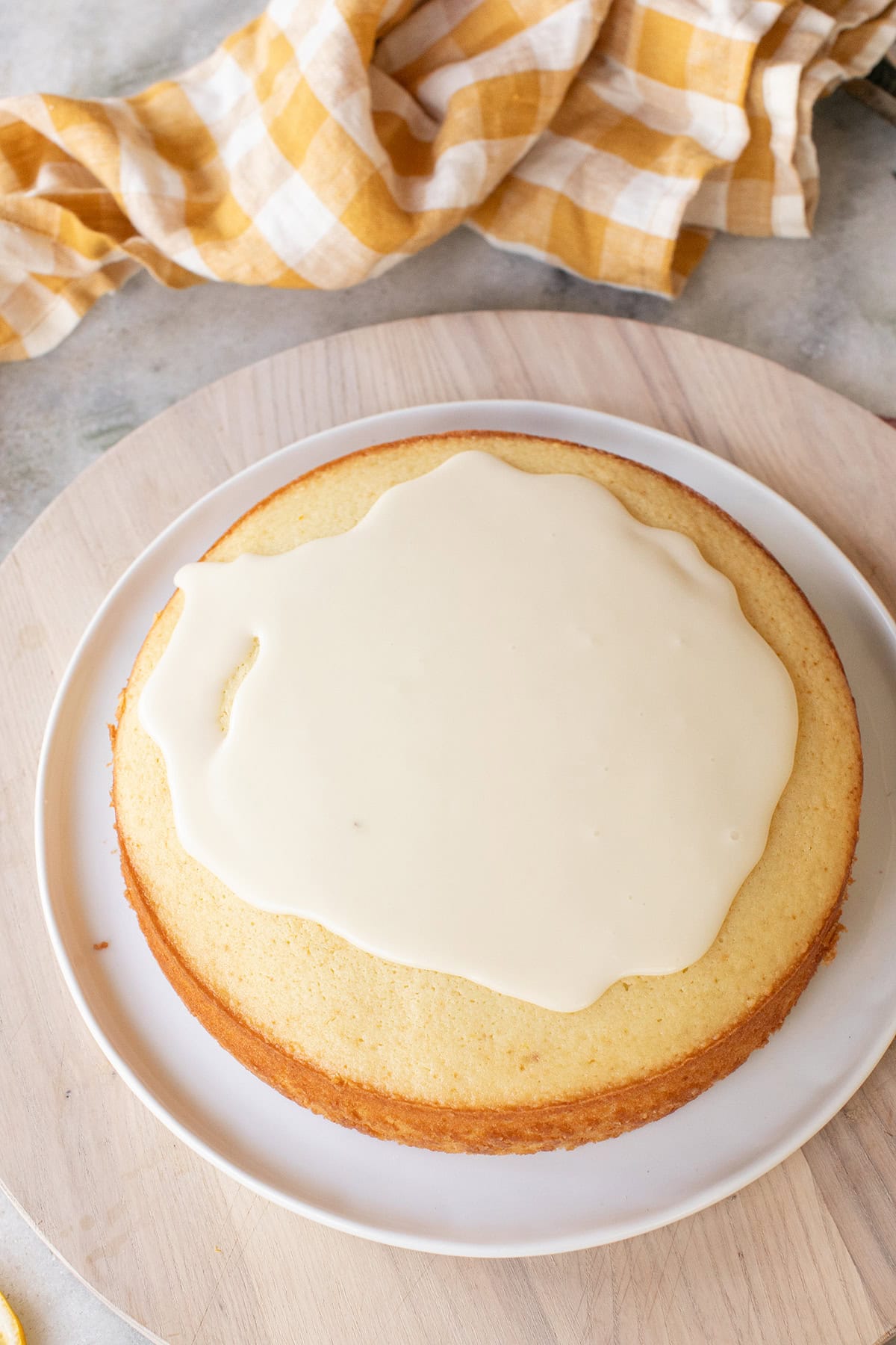 Pouring lemon olive glaze over a moist 9" round lemon cake.