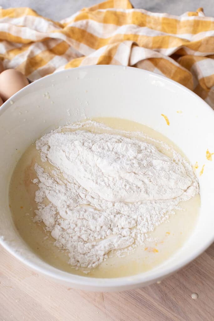 Adding dry ingredients to lemon olive oil cake batter before mixing.