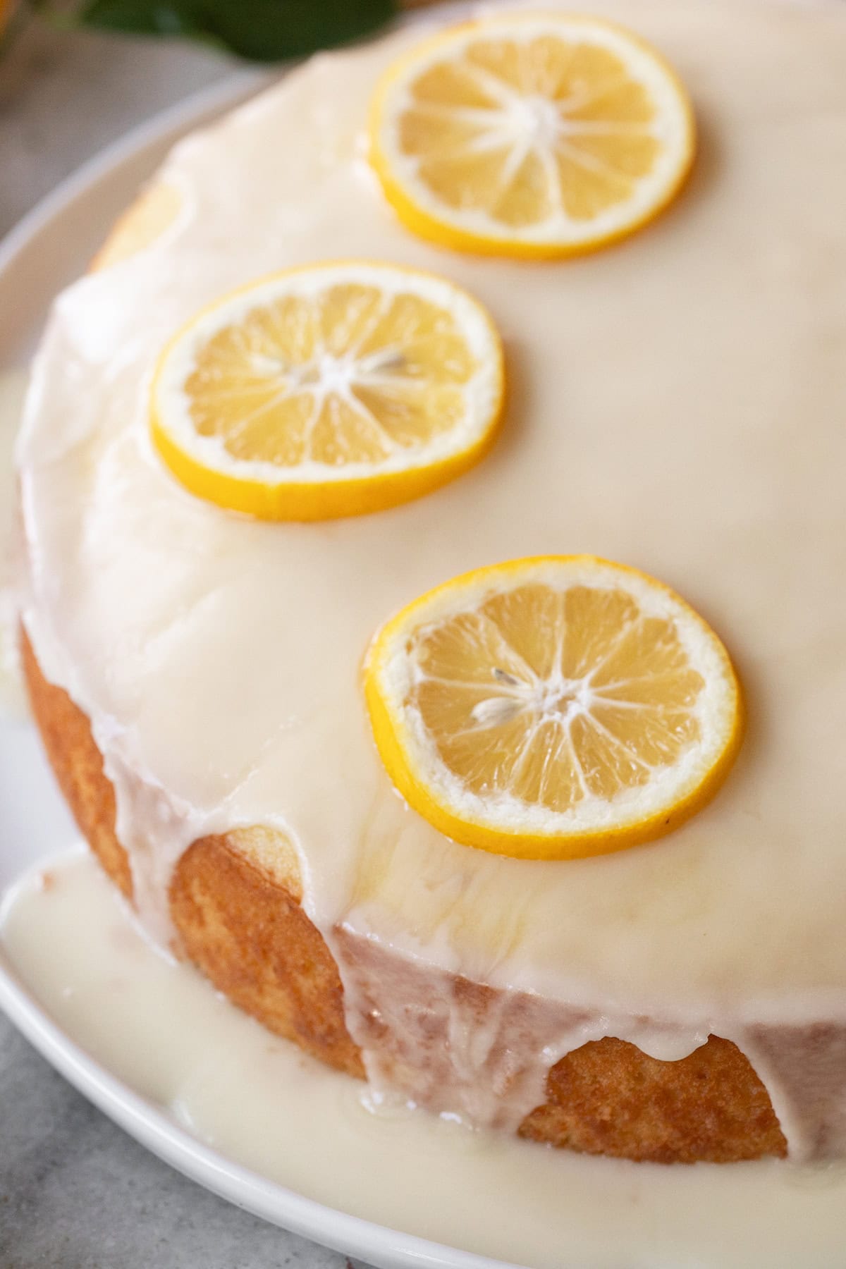 Close-up of moist lemon olive oil cake with lemon glaze and fresh lemons.