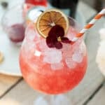 Blood orange spritz in a large wine glass with crushed ice and a blood orange slice garnish.