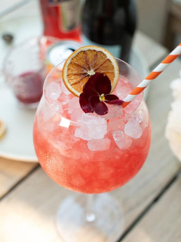 Blood orange spritz in a large wine glass with crushed ice and a blood orange slice garnish.