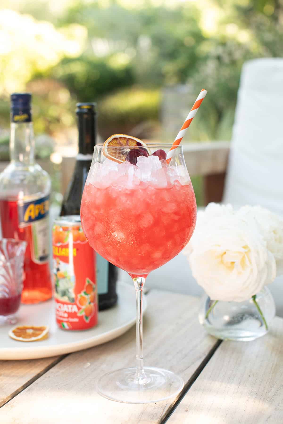 Blood orange spritz recipe in a large wine glass filled with ice.