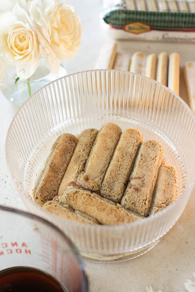 Layering in espresso dipped ladyfinger cookies in espresso for easy tiramisu recipe.