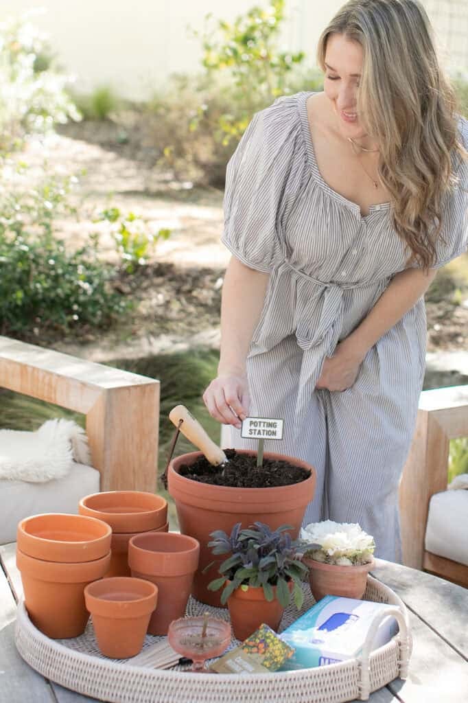 Eden Passante is adding seeds and dirt to a pot to plant flowers.