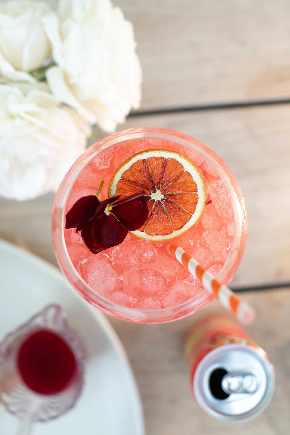 Blood orange spritz with an edible flower, dehydrated orange slices.