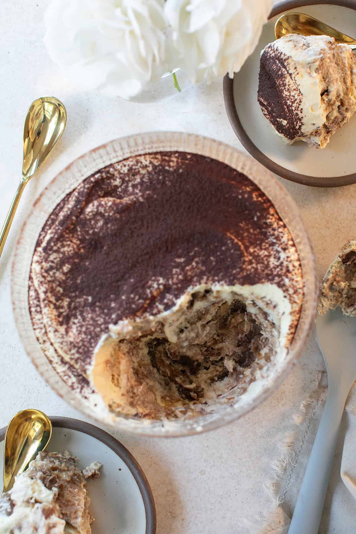 Easy tiramisu recipe served in a glass trifle dish showing layers of espresso soaked ladyfingers and creamy mascarpone filling.