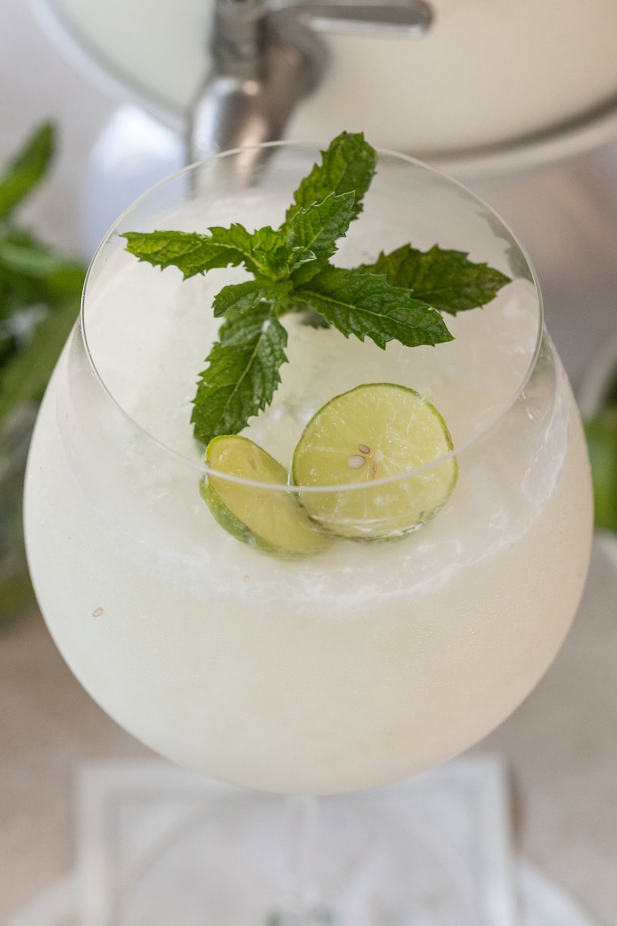 Creamy coconut margarita spritz served over ice in a large wine glass with a lime wheel.