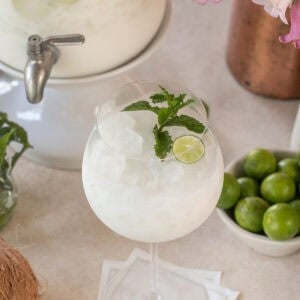 Coconut margarita cocktail topped with prosecco and garnished with mint.