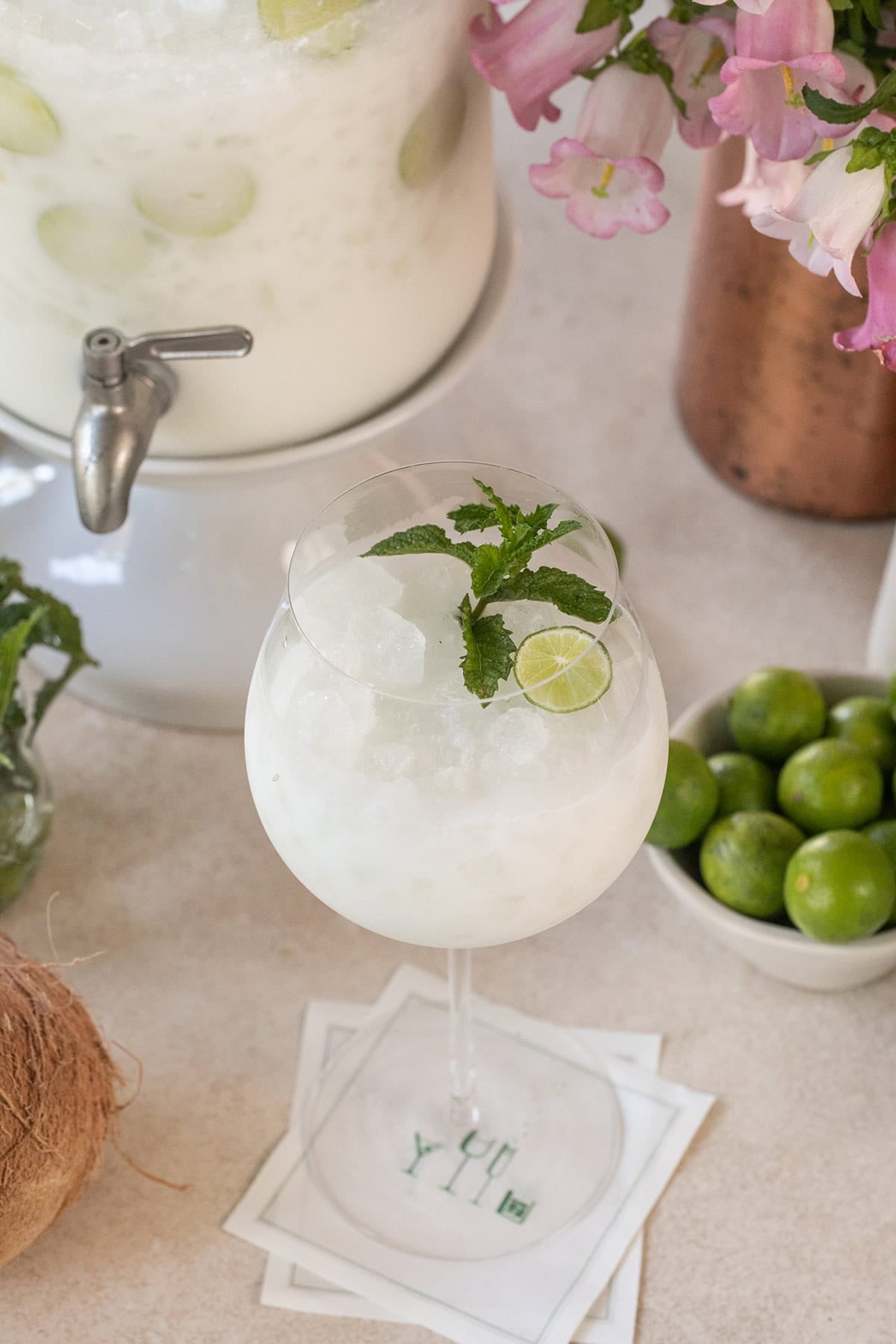 Coconut margarita cocktail topped with prosecco and garnished with mint.