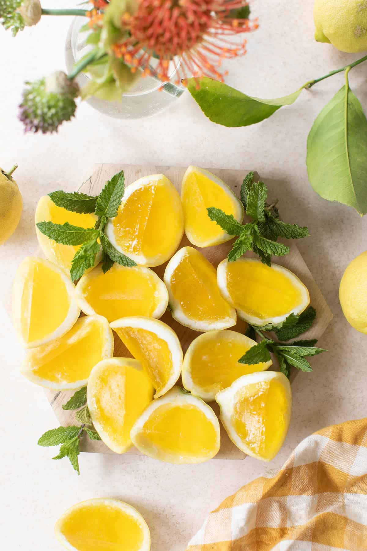Hugo spritz jello shot wedges on a platter with fresh mint and lemons for a summer party.