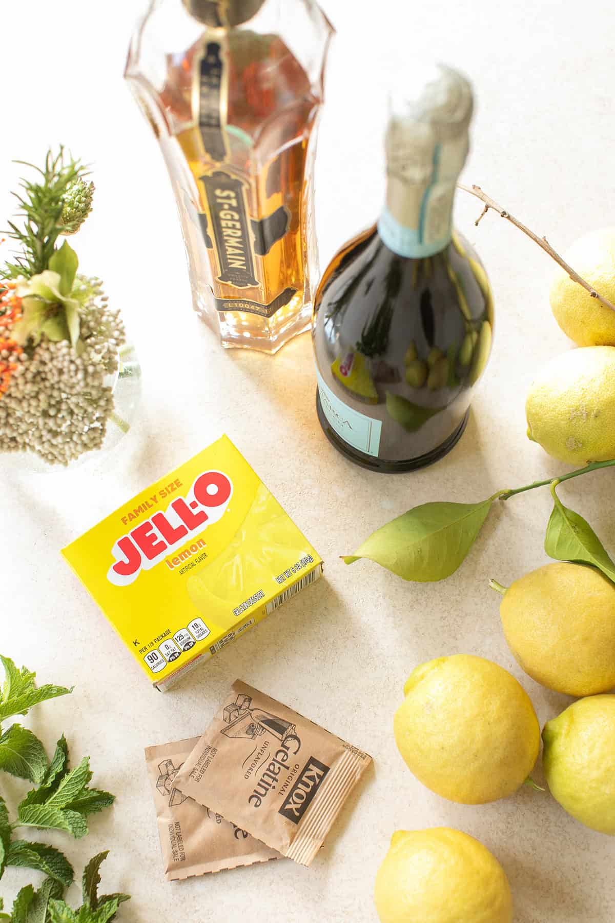 Ingredients for Hugo spritz jello shots including lemons, elderflower liqueur, Prosecco, and lemon Jello.