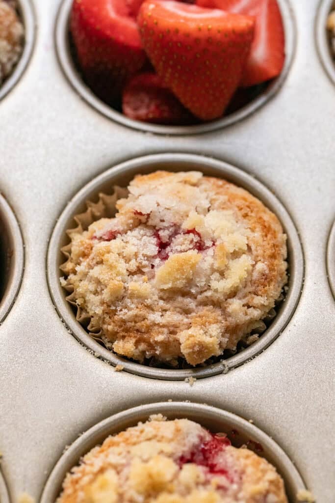 Baked strawberry streusel muffins cooling in a muffin tin.