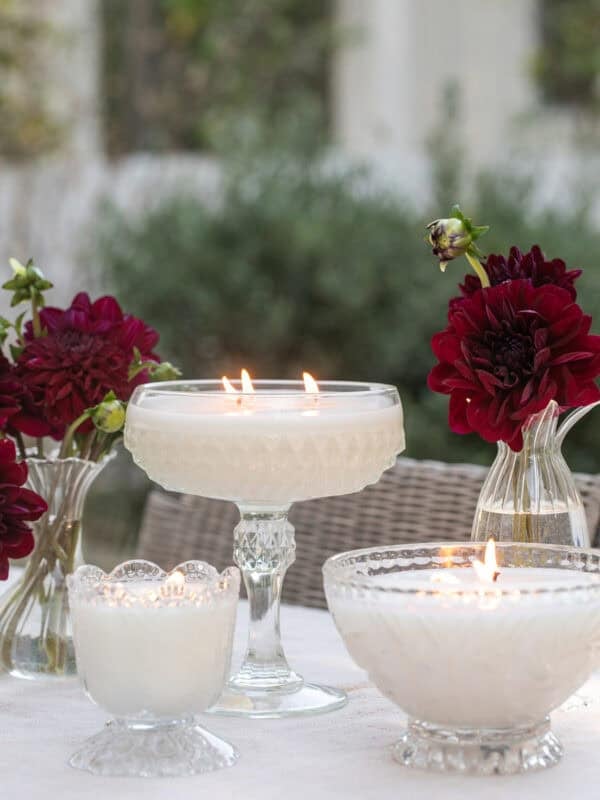 Homemade candles in vintage glassware glowing at night.