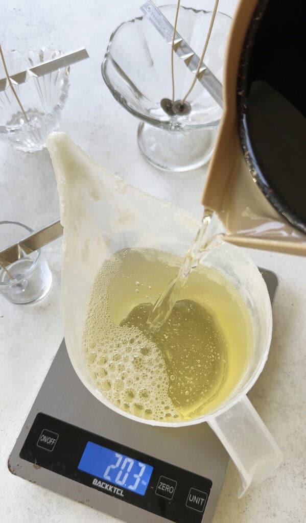 Pouring hot apricot coconut wax into a plastic pouring container to make candles.